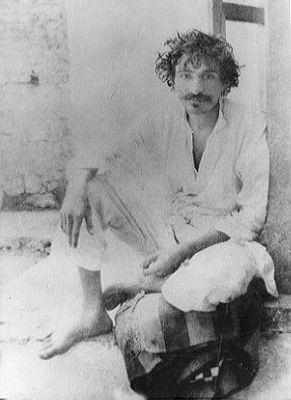 Seated on the ground with cloth on lap.