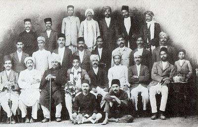 Poona, India. Meher Baba seated on the floor (right).