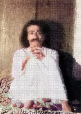Seated indoors in white robe.