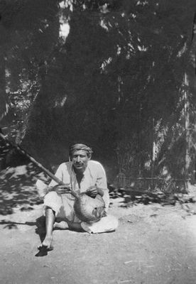 Seated outside the Poona Jhopdi with an ektara.